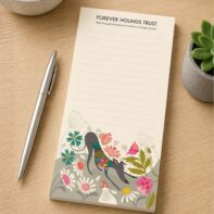 Forever Hounds Trust notepad featuring Rollerdog artwork displayed on an oak desk with pen and succulent